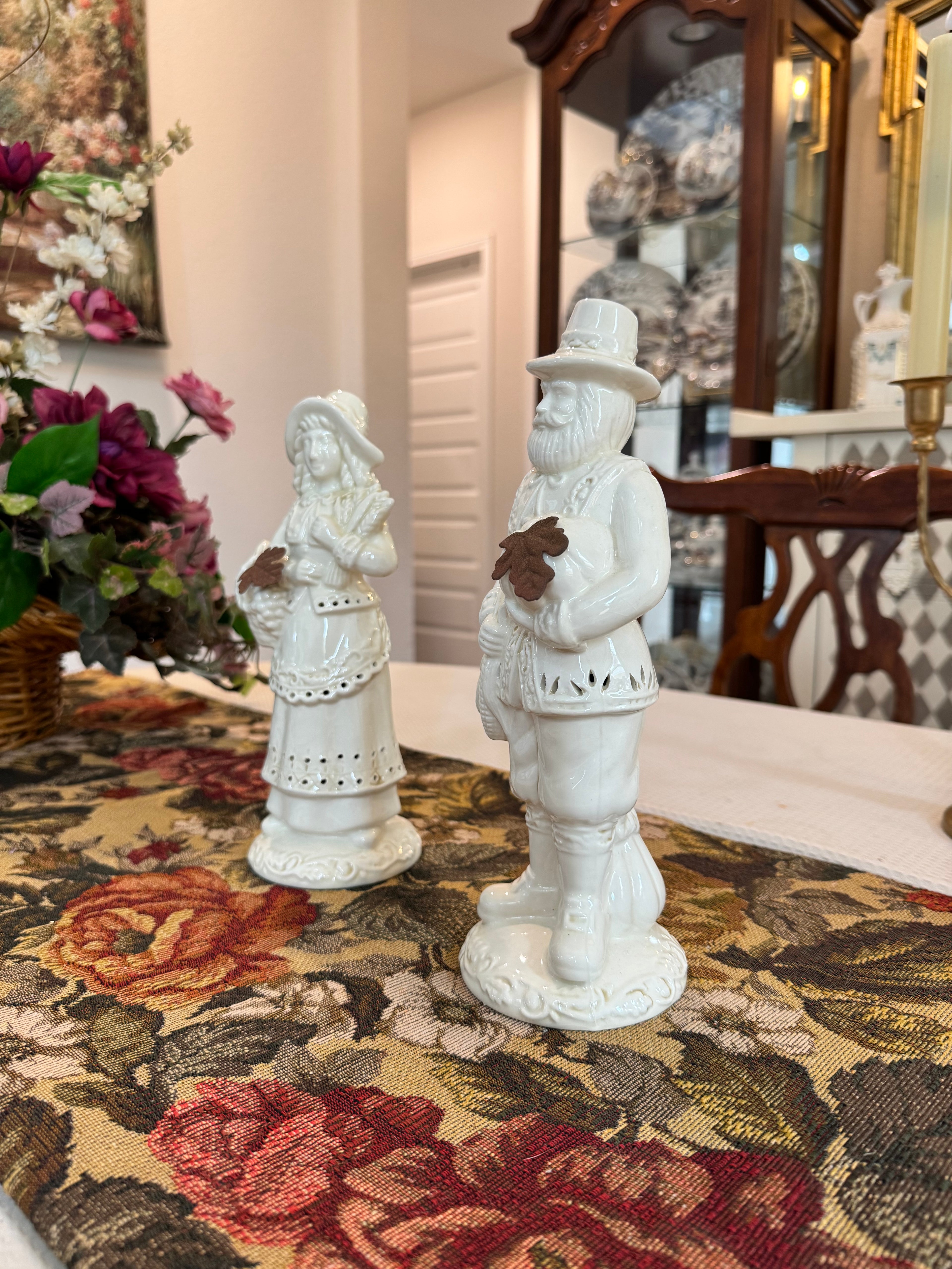 A pair of vintage white porcelain figurines depicting a Pilgrim man and woman