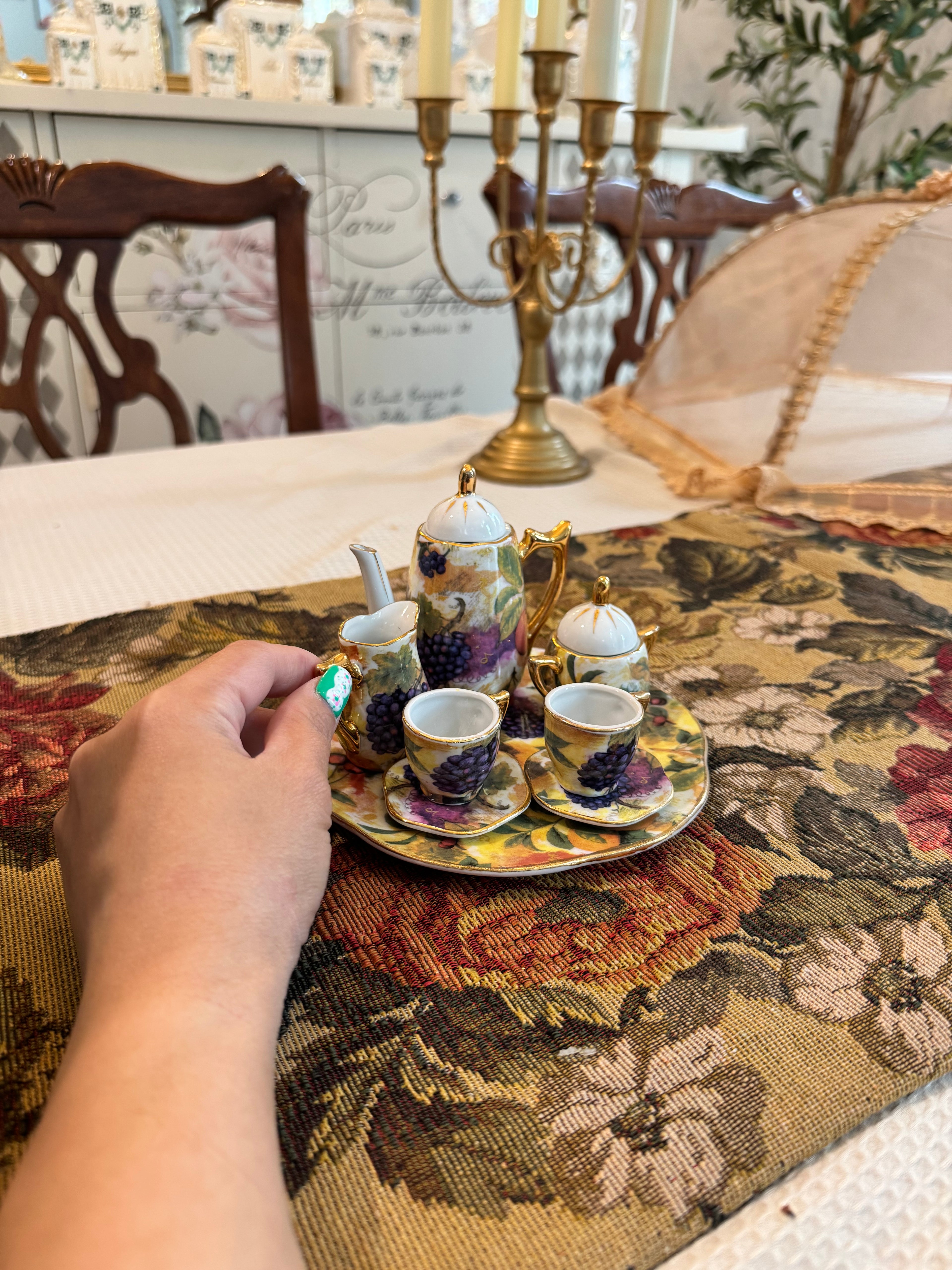 Vintage miniature porcelain tea set features a fruit motif pattern with gold gilt accents by Baum Bros Formalities.