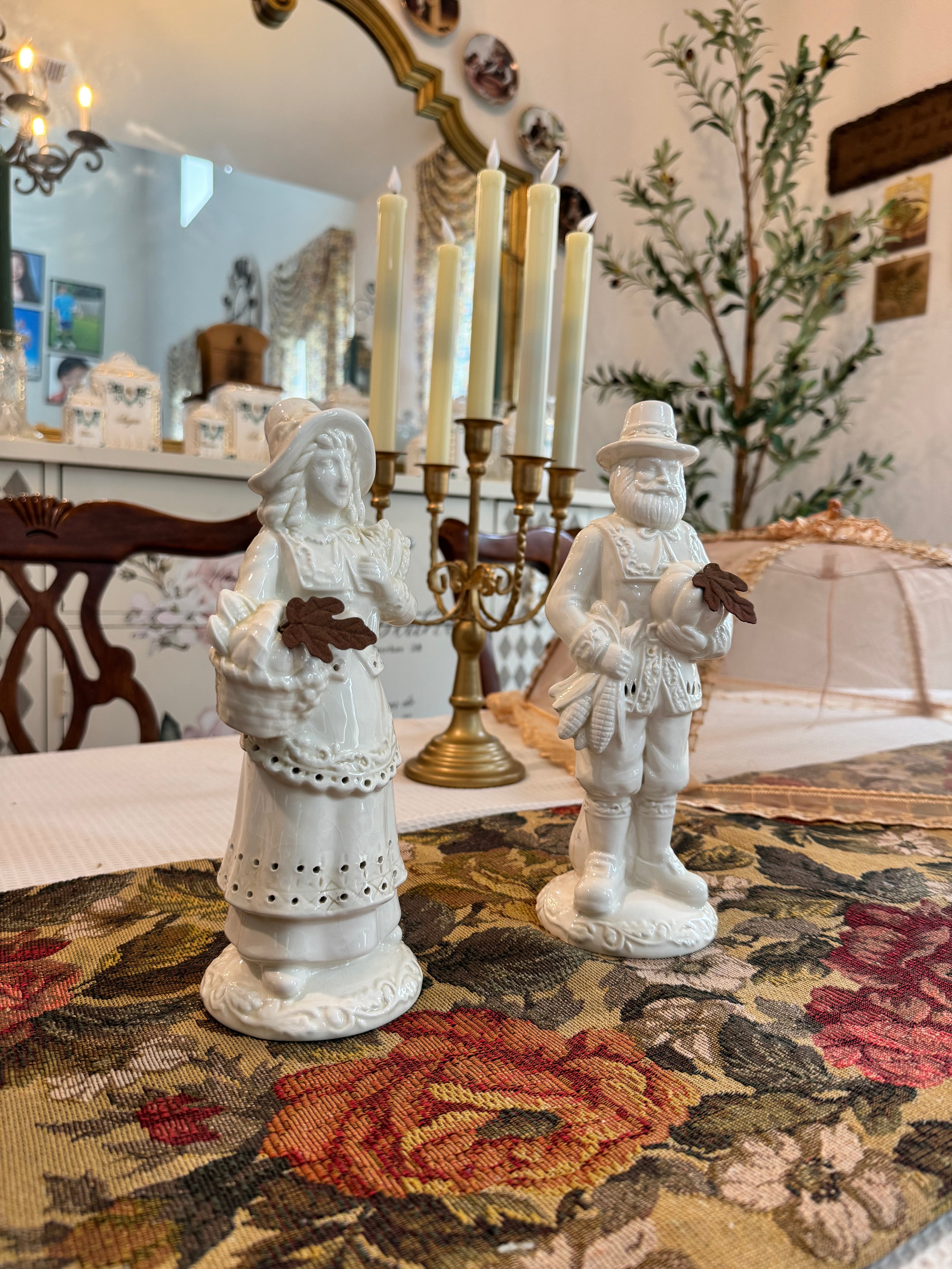 A pair of vintage white porcelain figurines depicting a Pilgrim man and woman