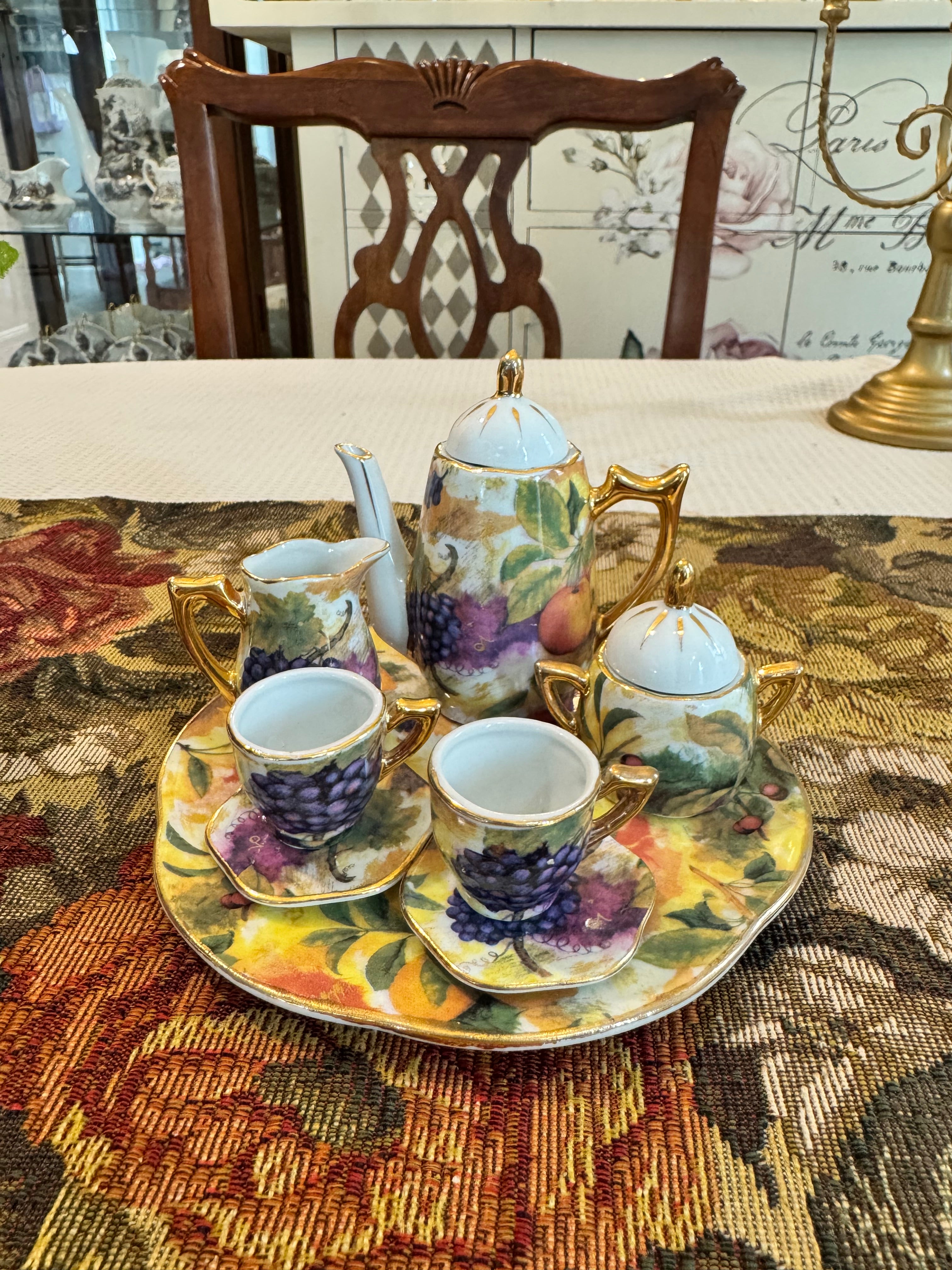 Vintage miniature porcelain tea set features a fruit motif pattern with gold gilt accents by Baum Bros Formalities.