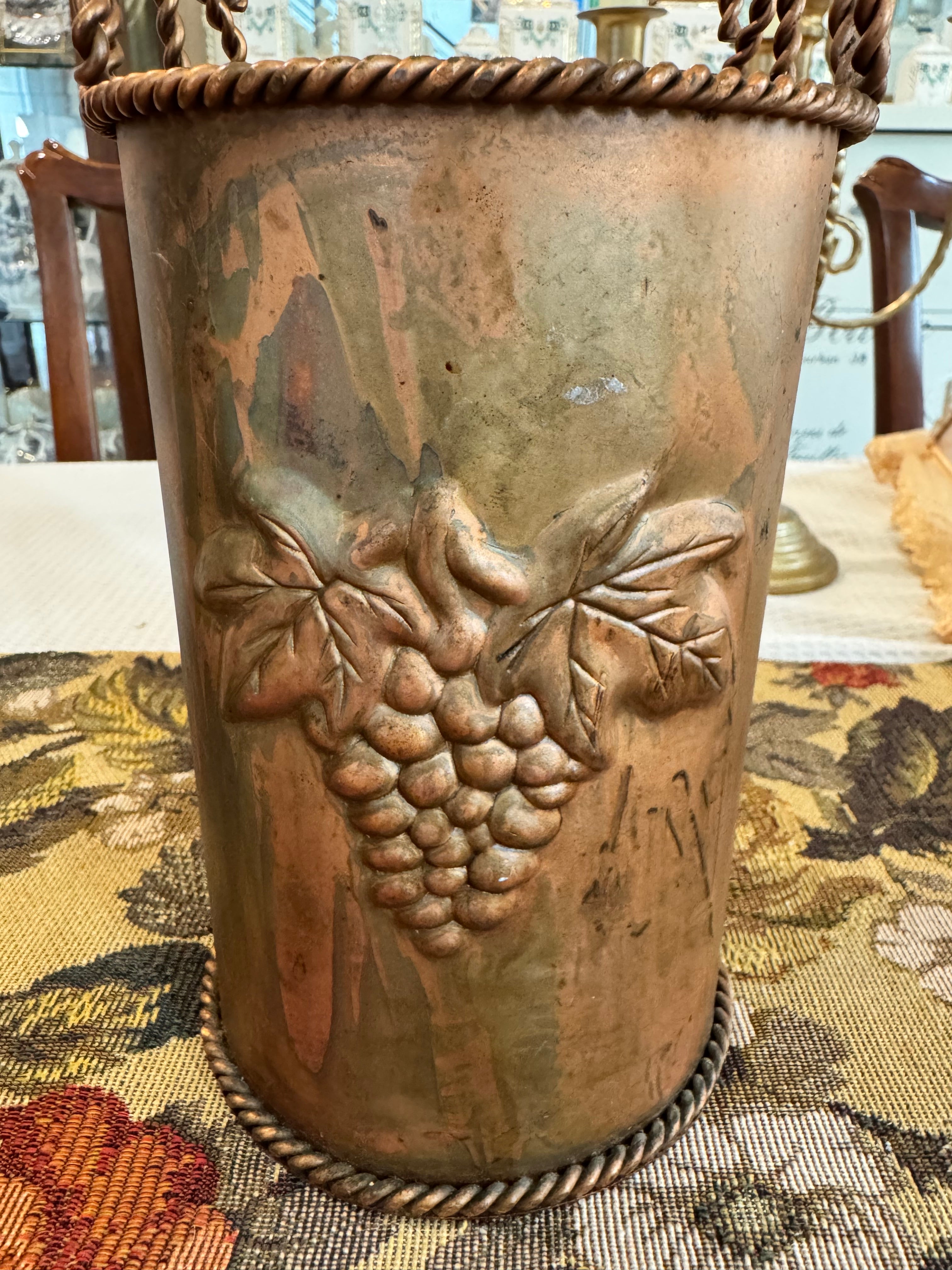 Vintage hammered copper wine or champagne cooler bucket with a twisted handle and grapevine embossing.