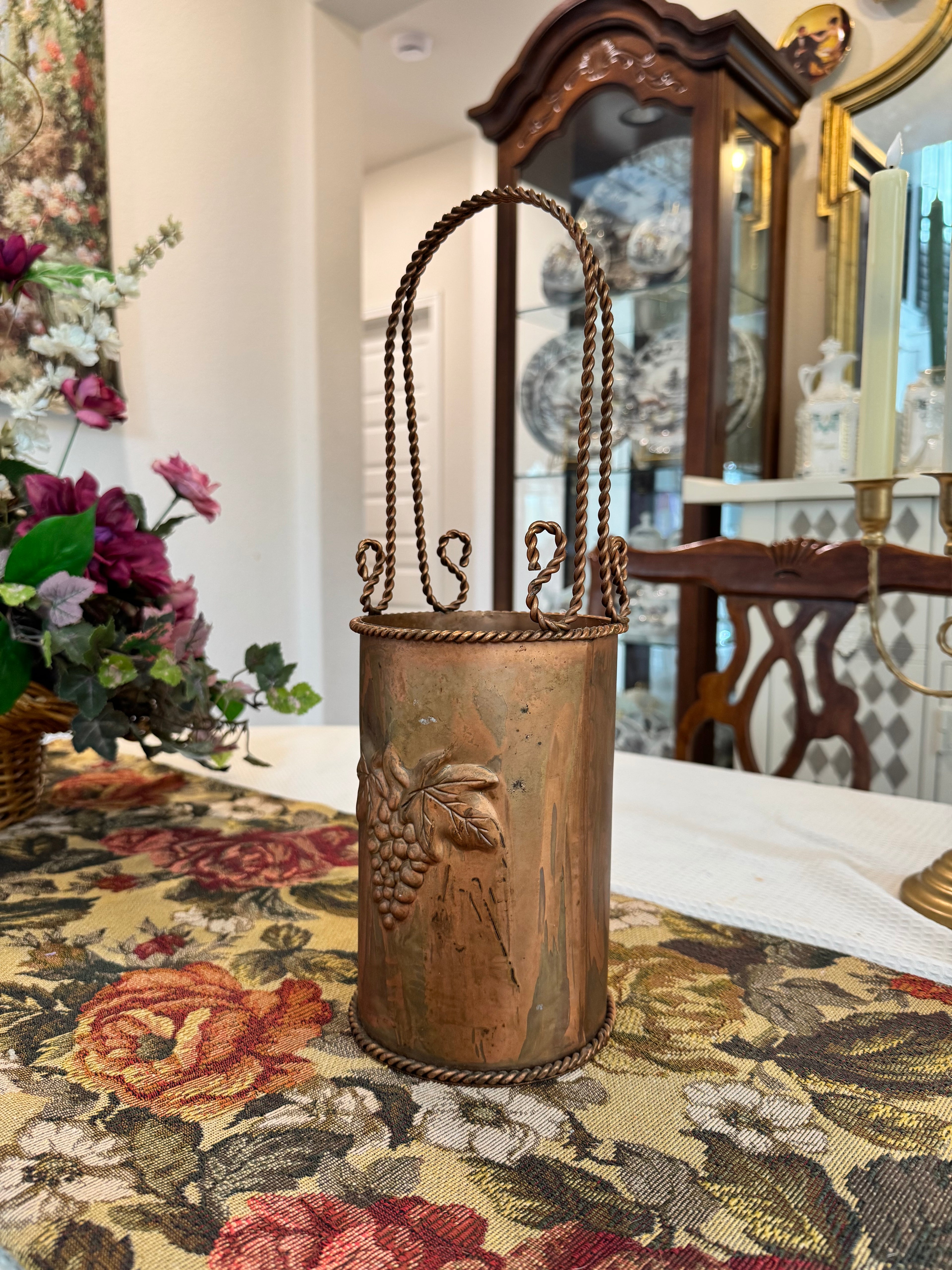 Vintage hammered copper wine or champagne cooler bucket with a twisted handle and grapevine embossing.