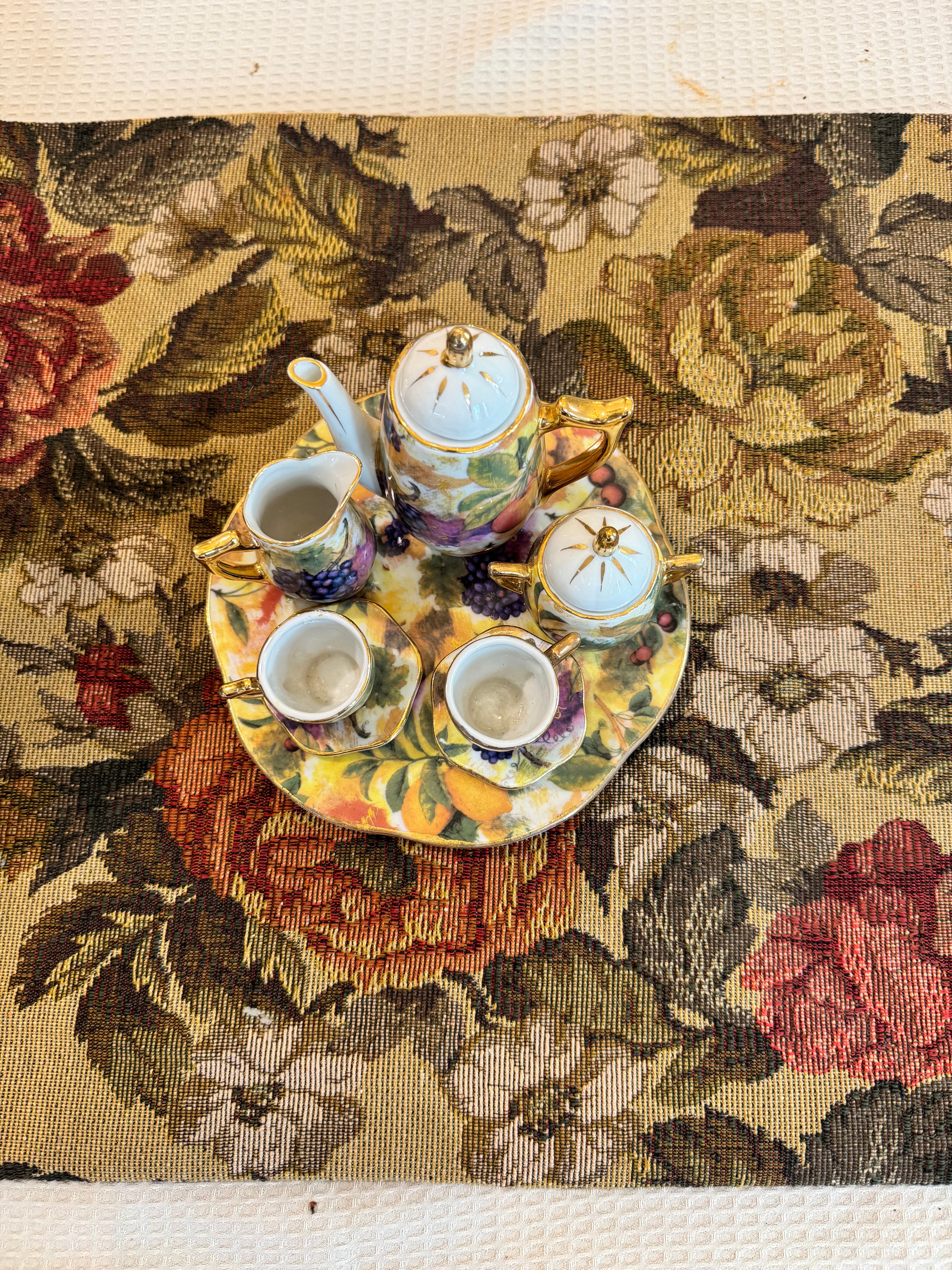 Vintage miniature porcelain tea set features a fruit motif pattern with gold gilt accents by Baum Bros Formalities.